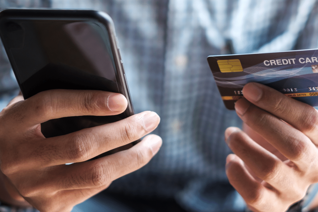 pessoa usando celular e cartão de crédito para realizar compra online