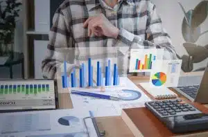 Indicadores de desempenho para ecommerce: mesa com vários gráficos holográficos em frente a uma pessoa vestida com camisa xadrez