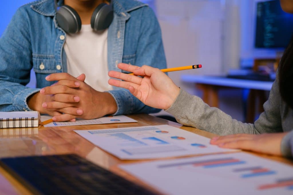 Estratégias de SEO marketing: duas pessoas conversando com gráficos em cima de uma mesa.