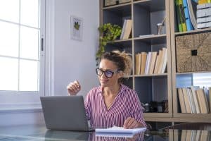 Guia de Marketing de Conteúdo: mulher de camisa listrada e óculos olhando para o notebook.