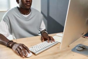 Links internos: homem negro usando computador com mouse e teclado.