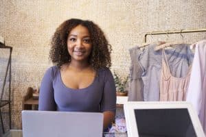 Google Meu Negócio. Mulher negra usando computador em loja de roupa.