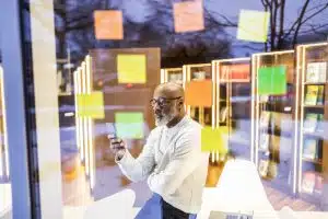 SEO para migração de e-commerce. Homem olha a tela do celular entre post-its